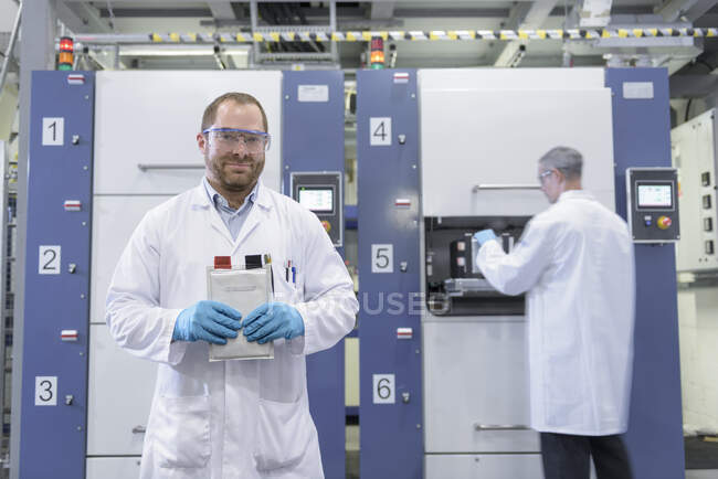 Wissenschaftler mit Lithium-Ionen-Beutelherstellungsmaschine in Batterie-Forschungseinrichtung, Porträt — Stockfoto