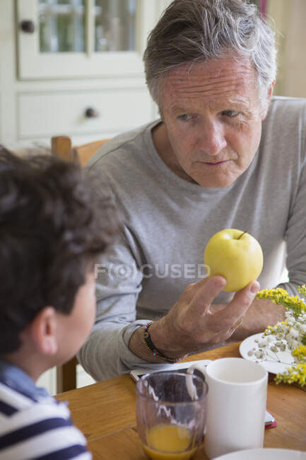 Grandfather offering apple to grandson — Stock Photo