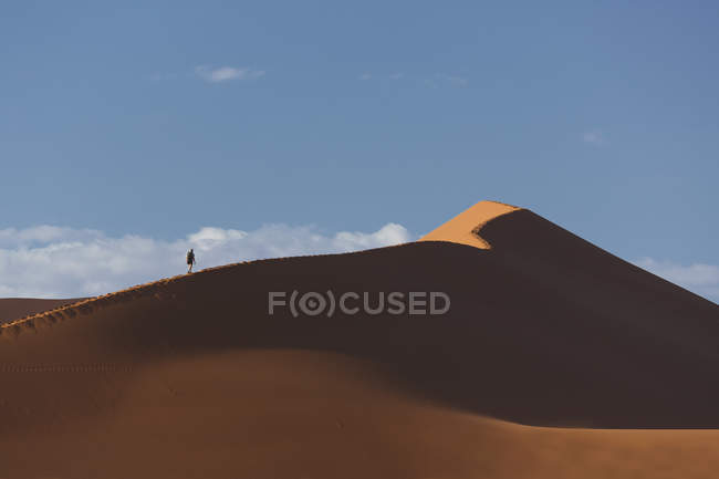Silueta del hombre senderismo en duna de arena gigante - foto de stock