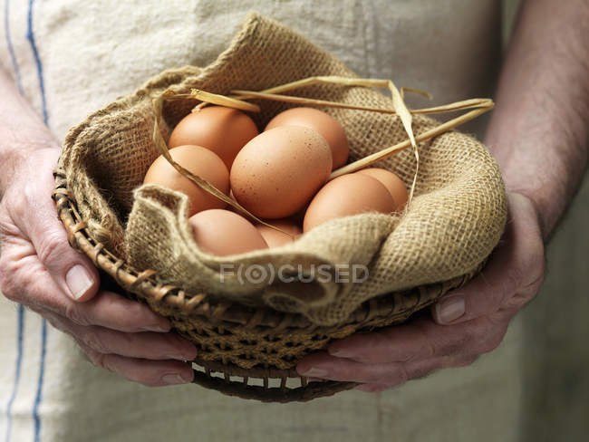Старшая женщина держит яйца в винтажной ткани и корзине — стоковое фото