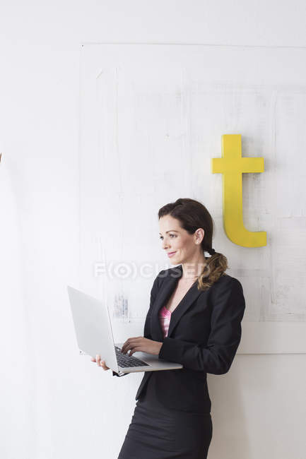 Femme mature en tenue de travail à l'aide d'un ordinateur portable — Photo de stock