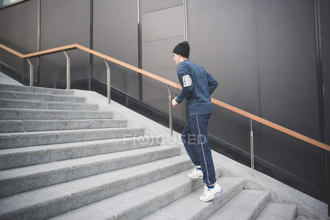 Junge männliche Läuferin steigt Stadttreppe hinauf — Stockfoto