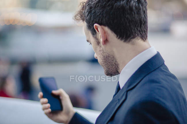 Sobre la vista del hombro de los mensajes de texto de hombre de negocios en el teléfono inteligente - foto de stock