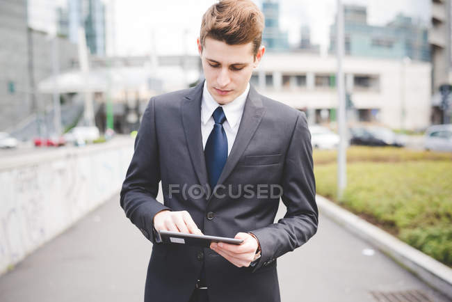 Porträt eines jungen Geschäftsmannes, der mit dem digitalen Tablet pendelt. — Stockfoto