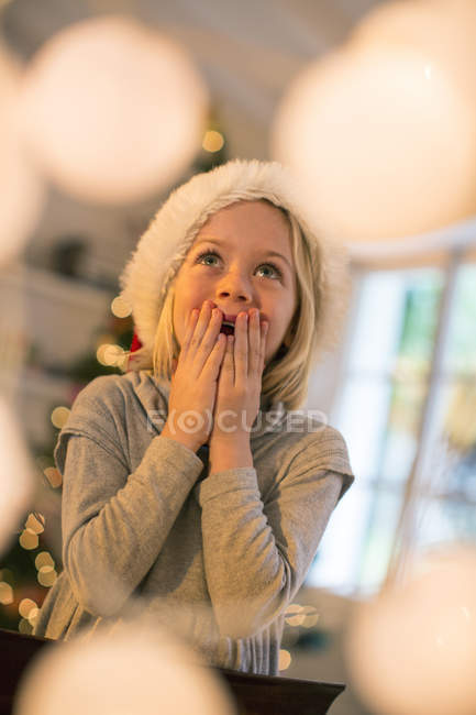 Girl in Christmas hat looking up in awe — Stock Photo