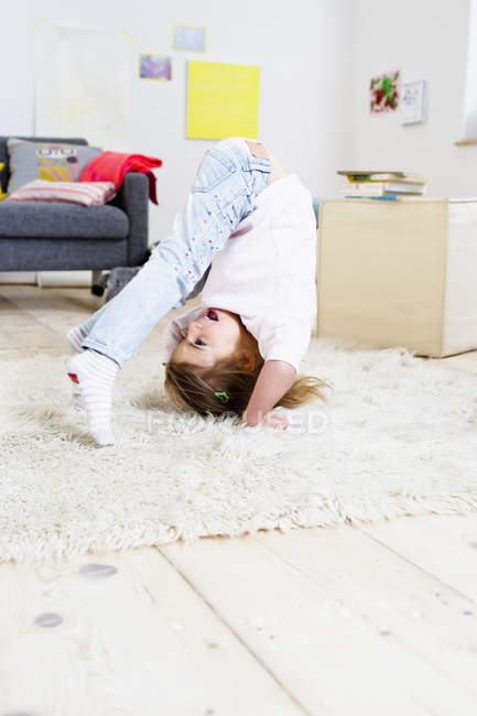 Ragazza cercando di fare headstand a casa — Foto stock