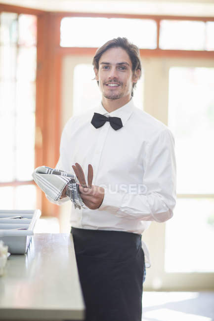 Portrait of waiter polishing cutlery in restaurant — Stock Photo