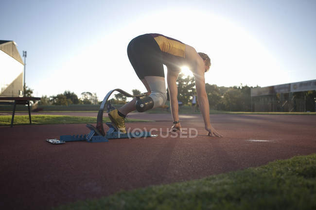 Sprinter masculino incapacitado em posição inicial no estádio — Fotografia de Stock
