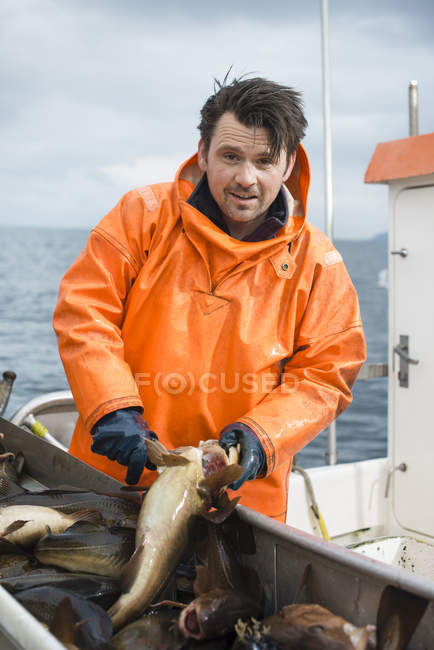 Pescador no barco segurando peixes e olhando para a câmera — Fotografia de Stock