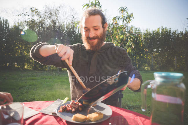 Young man holding frying pan serving food — Stock Photo