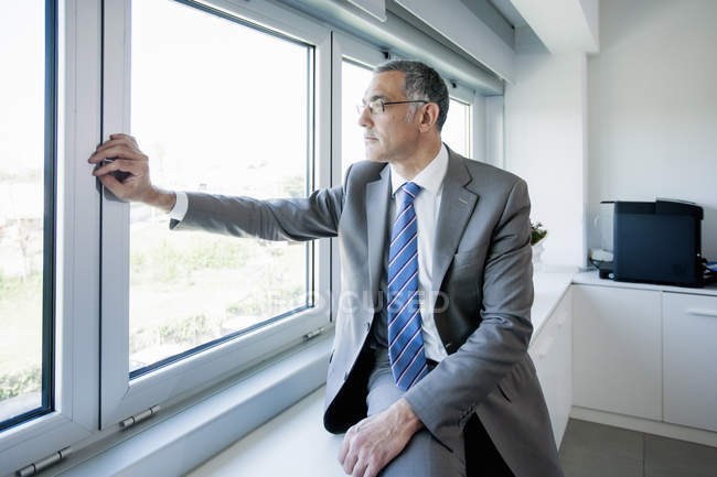 Älterer männlicher Geschäftsmann schaut aus dem Bürofenster — Stockfoto