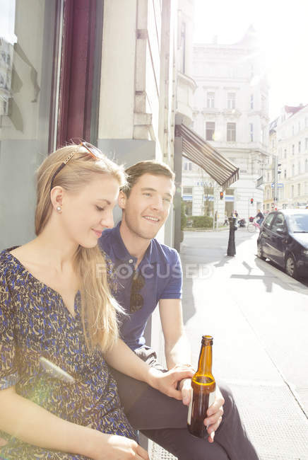 Молодая пара в кафе на тротуаре пьет пиво — стоковое фото