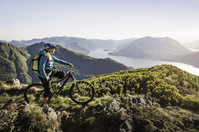 Giovane donna in mountain bike, vista lago di Como, Italia — Foto stock