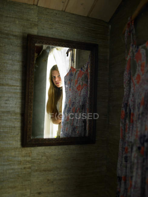 Reflexão do espelho da menina adolescente espreitando da porta do quarto — Fotografia de Stock