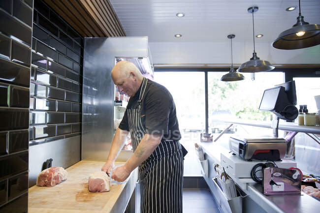 Boucher mature préparant la viande dans la boucherie — Photo de stock