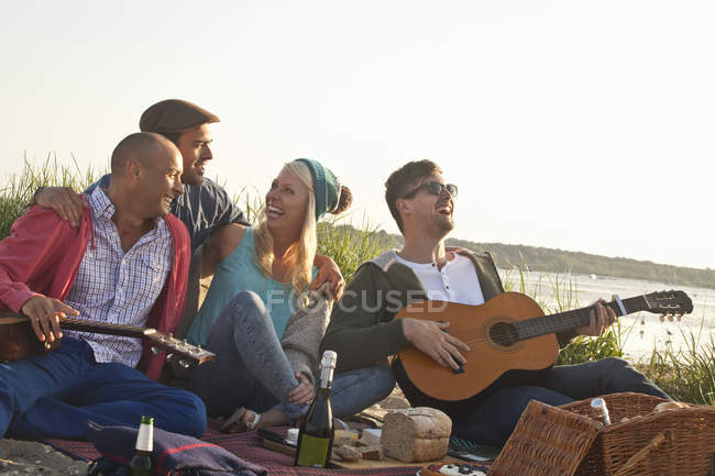 Cuatro amigos celebrando una fiesta en la playa de Bournemouth, Dorset, Reino Unido - foto de stock