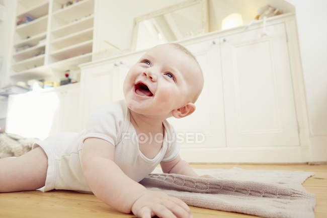 Smiling baby boy crawling on sitting room floor — Stock Photo