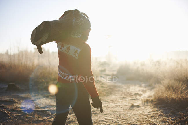 Homme portant des bûches dans le paysage rural — Photo de stock