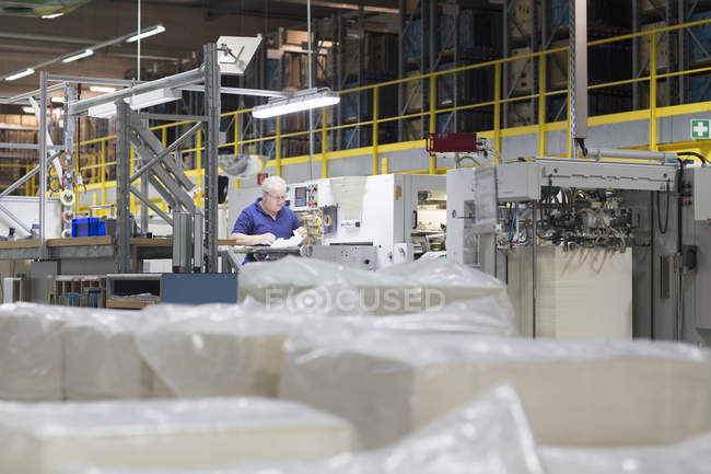 Trabajador que utiliza la máquina en fábrica de embalaje de papel - foto de stock