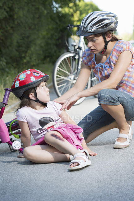 Мати доглядає за дочкою впала з велосипеда — стокове фото