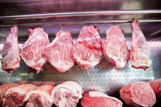 Rows of meat joints hanging in refrigerator — Stock Photo