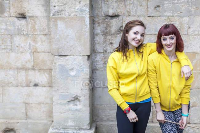 Giovani donne sorridenti, muro di pietra sullo sfondo — Foto stock