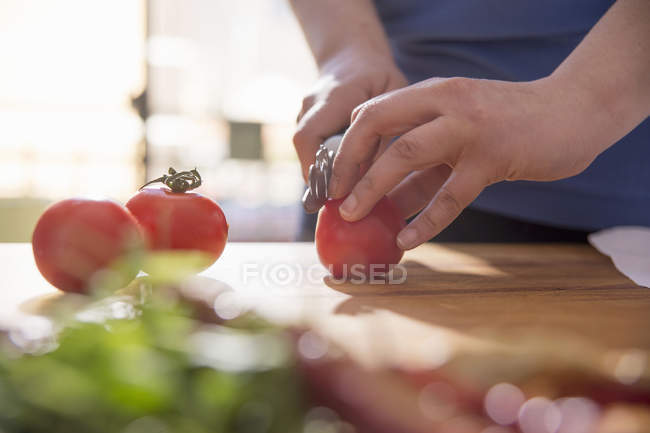 Image recadrée de femme tranchant la tomate au comptoir de la cuisine — Photo de stock