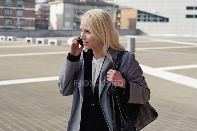 Femme d'affaires, marchant à l'extérieur, utilisant un téléphone mobile — Photo de stock
