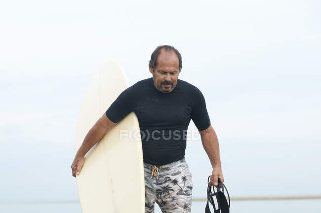 Surfista che trasporta la tavola da surf sulla spiaggia — Foto stock
