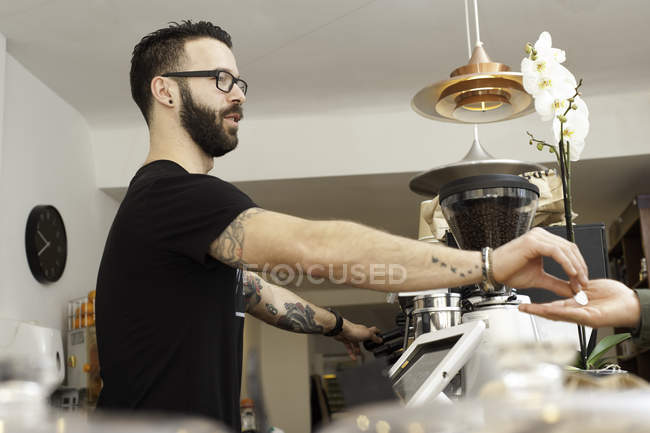 Cafe waiter handing coins to customer from behind counter — Stock Photo