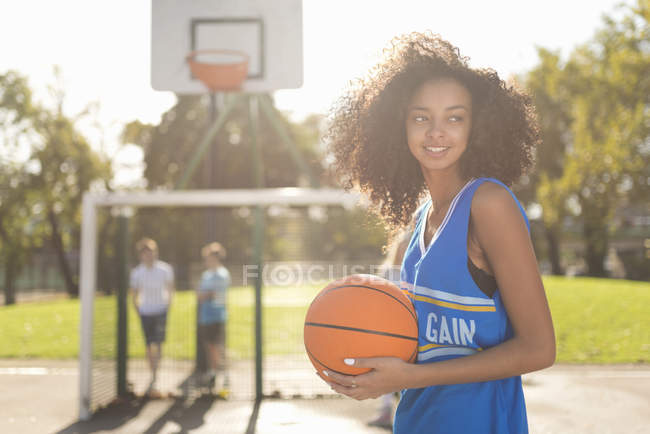 Sonriente joven jugador de baloncesto femenino celebración de baloncesto - foto de stock