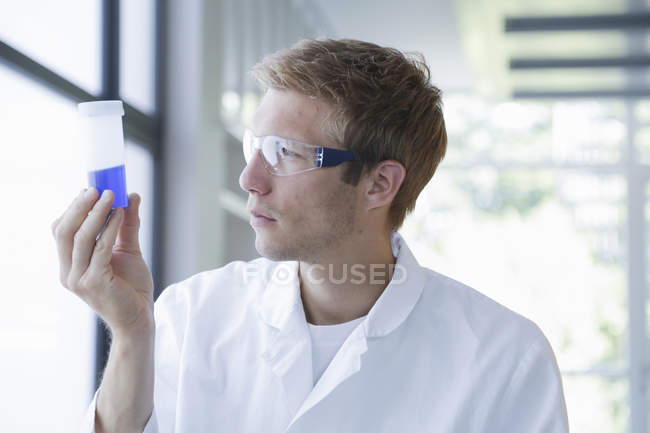 Cientista do sexo masculino analisando amostra em garrafa de plástico em laboratório — Fotografia de Stock
