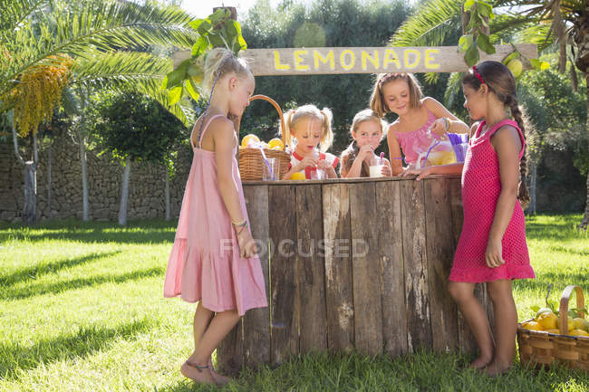 Cinco meninas derramando limonada e conversando no quiosque de limonada no parque — Fotografia de Stock