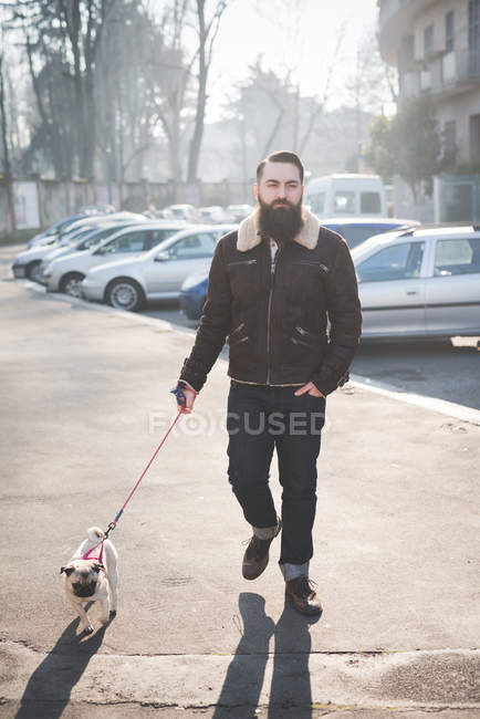 Jeune homme barbu chien ambulant dans la rue — Photo de stock