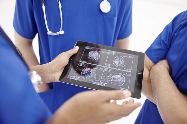 Médicos mirando escaneos en tableta digital - foto de stock