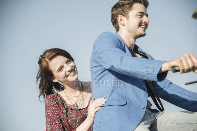 Jeune couple partageant vélo — Photo de stock