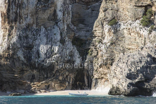 Barco ancorado na água por caverna em penhasco — Fotografia de Stock