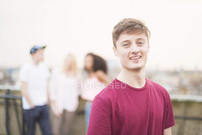 Молодий чоловік у червоній футболці на вулиці з людьми на задньому плані — стокове фото