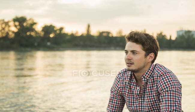 Молодий чоловік у перевіреній сорочці біля озера — стокове фото