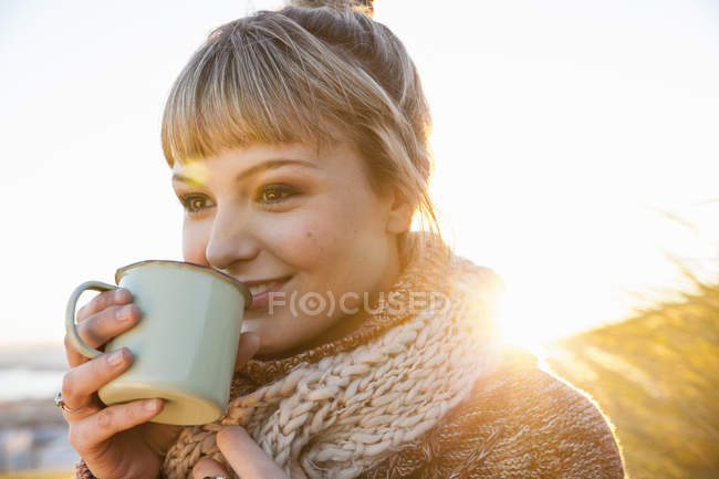 Portrait of young woman in sunlit marsh with drinks mug — Stock Photo