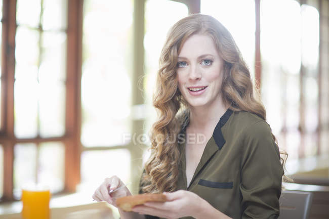 Young woman sitting at restaurant table with slice of toast — Stock Photo