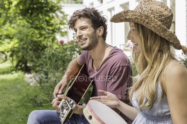 Молодой человек играет на гитаре, женщина с бубном — стоковое фото