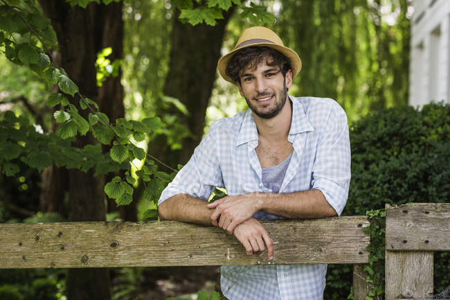 Retrato do jovem encostado à cerca de madeira — Fotografia de Stock