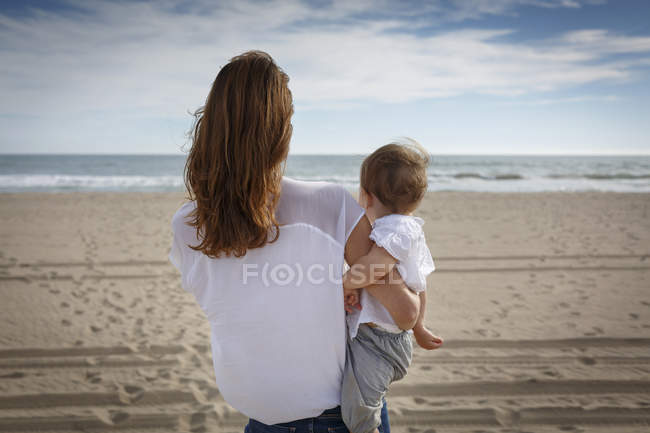 Rückansicht von Frau und Kleinkind-Tochter mit Blick aufs Meer, castelldefels, Katalonien, Spanien — Stockfoto
