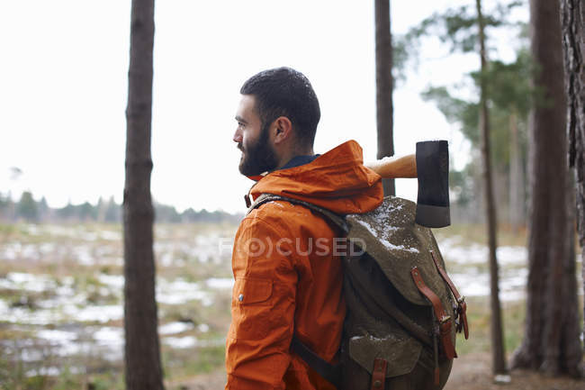 Jeune homme portant hache regardant de la forêt — Photo de stock