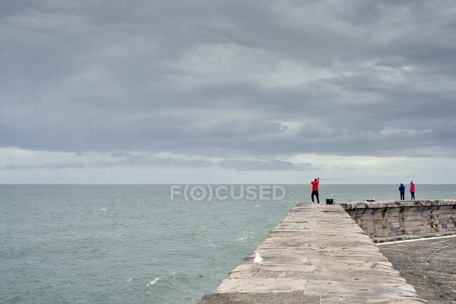 Fisherman casting from harbour wall, Cumbria, Regno Unito — Foto stock