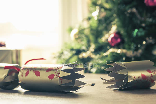 Used Christmas cracker on table with fir tree on background — Stock Photo