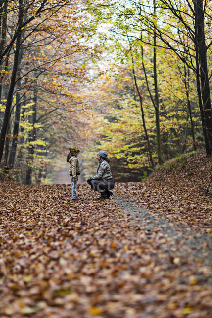 Madre e hija en bosque otoñal - foto de stock