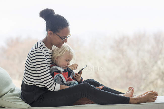 Madre e hijo sentados juntos usando tableta - foto de stock