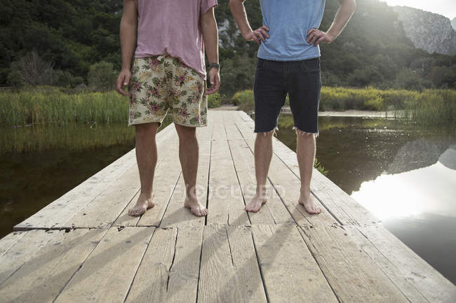 Waist down front view of young men on wooden pier, Cala Luna, Sardinia, Italy — Stock Photo
